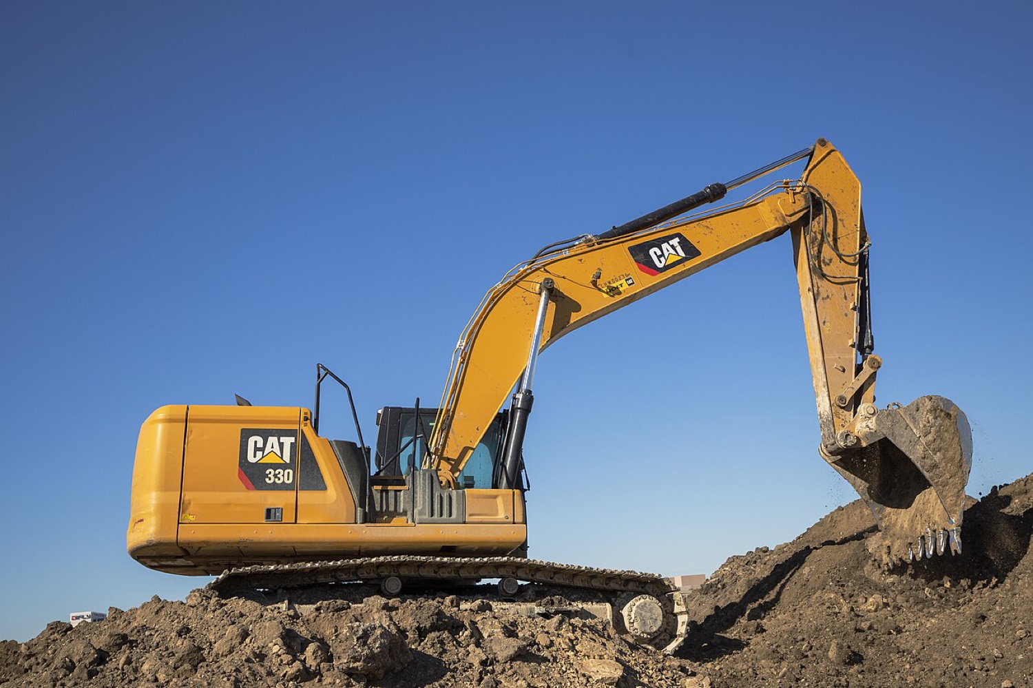 Şantiyede toprak yığını üzerinde çalışan Caterpillar 330 paletli ekskavatör